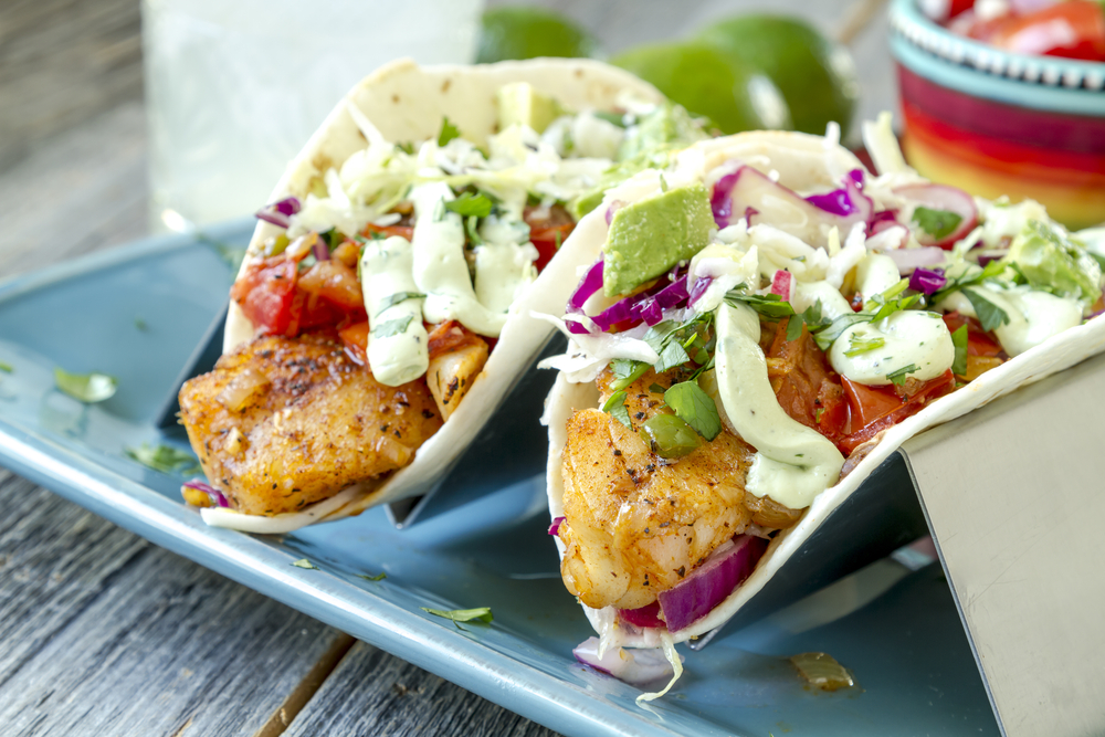 Two fish tacos sit in dividers and are toped with sauce, cabbage, pico, and more at one of the best restaurants in Siesta Key.