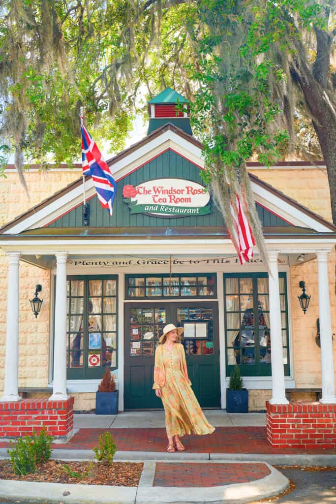 woman in a yellow dress standing outside of a tea room with british flags in Mount Dora Florida