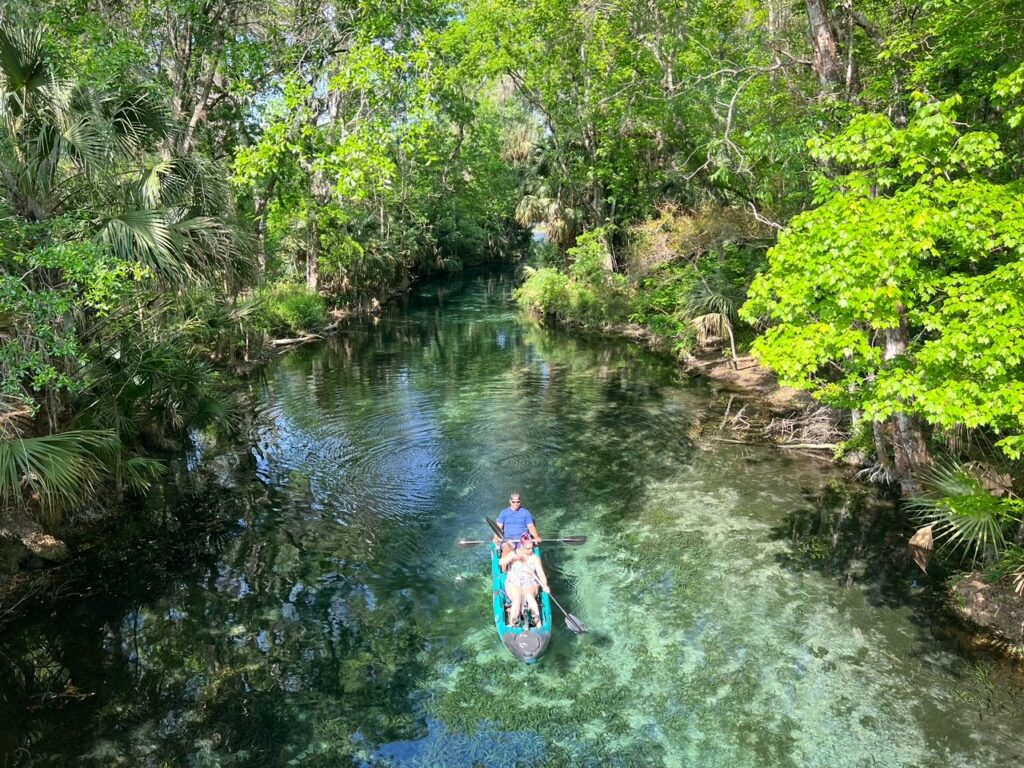 A couple paddles down a river at Silver Springs state park in a double canoe. 