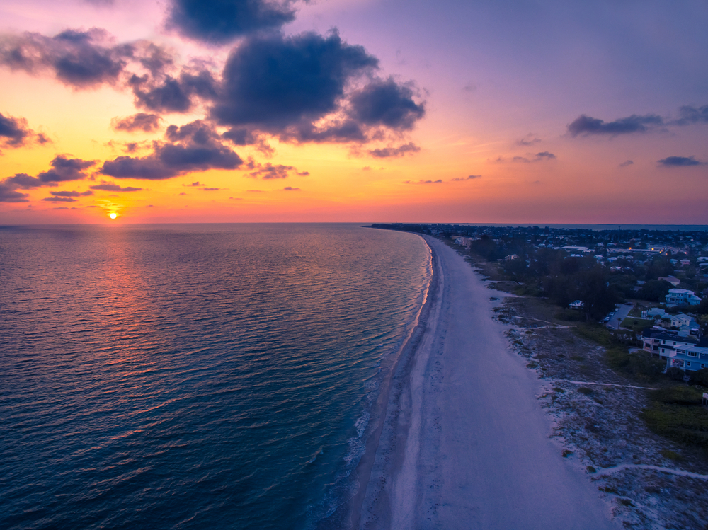 aerial view of the beach with the sun setting in the distance