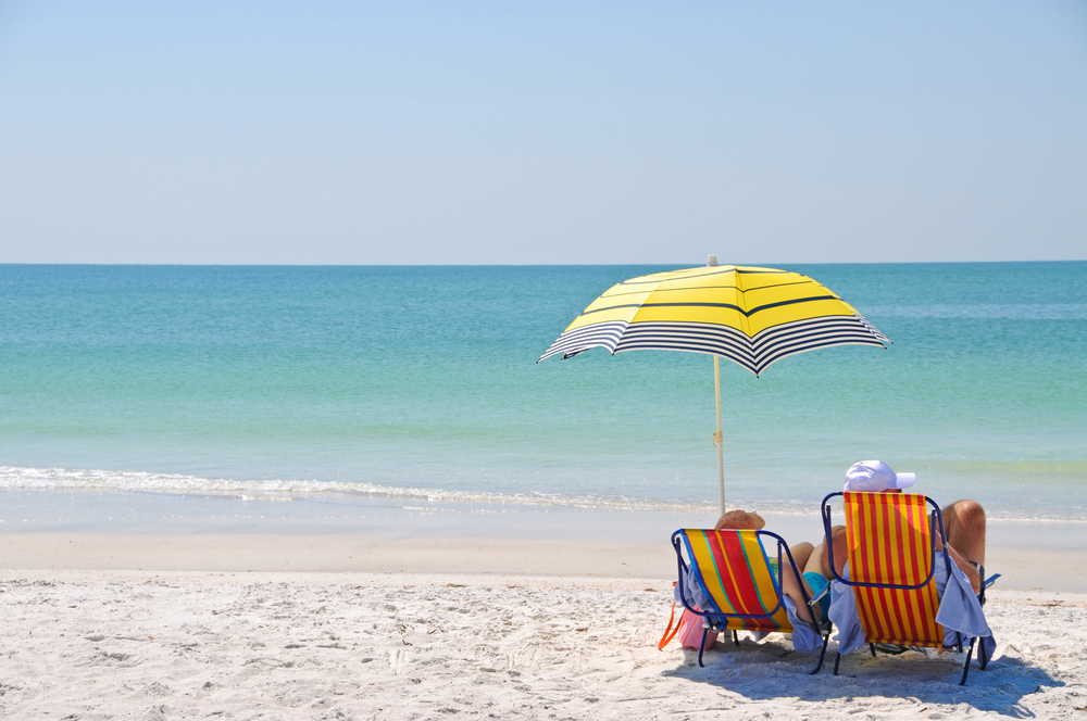 couple sitting on a beach chair on a beach with turquoise water beaches in anna maria island