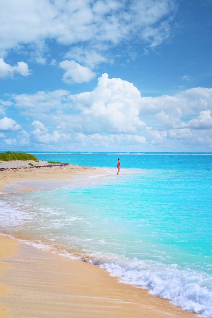 A woman stands in the tide along the bright blue ocean in the Florida Keys.