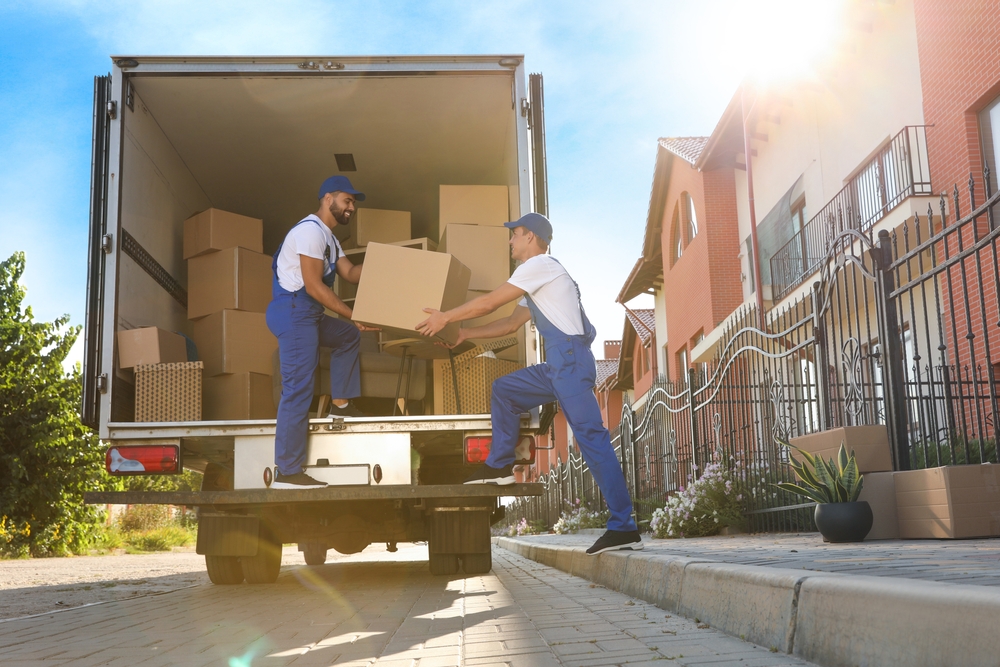 Two movers haul boxes into a moving truck.. if you are considering moving to Florida and living in Florida, then take the moving process into consideration! 
