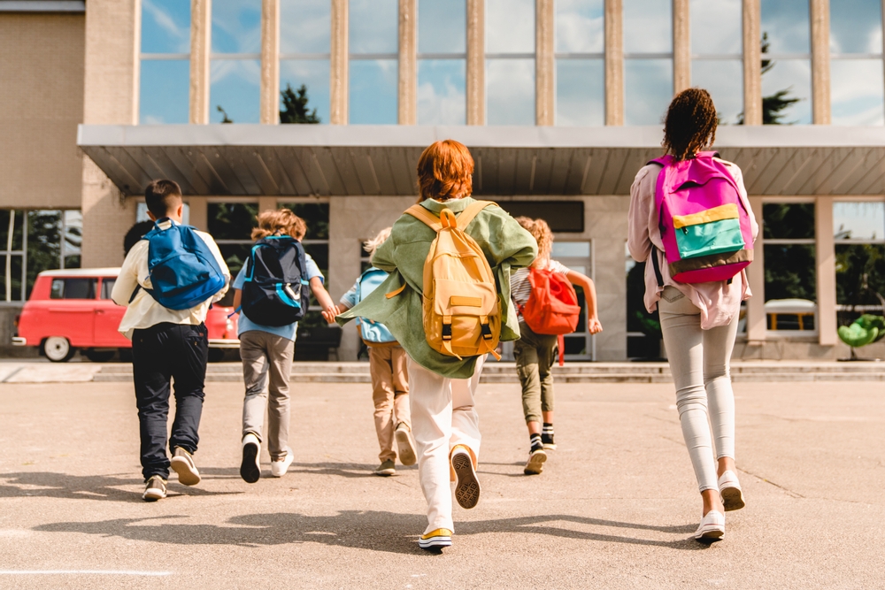 A con of living in Florida is the education system: public schools rank fairly low nationally. In this photo kids run toward school doors with their backpacks. 