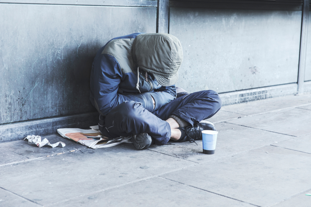 A homeless individual sits on the corner of a street with a cup in front of them asking for money. Homelessness due to the housing prices in Miami has become a big issue. 