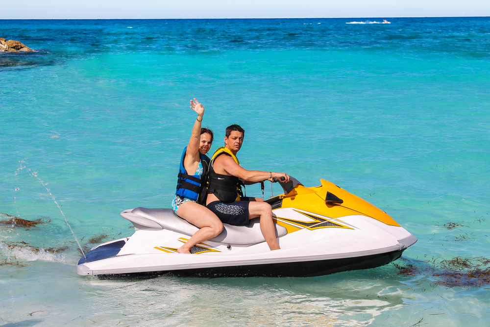 Living in Miami also has tons of recreational pros: this couple sits on a jet ski and waves at the camera, excited to spend time outdoors. 