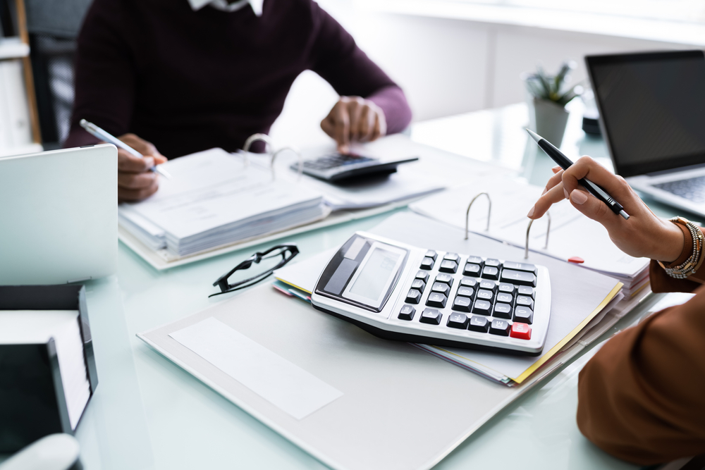 Living in Miami has some pros, like the lack of state taxes. People sit down and calculate their property taxes in this photo with binders of paper work and calculators. 