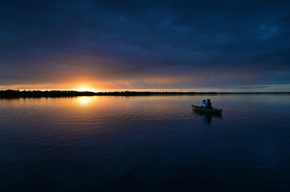 Kayaker in open water at sunset in Florida getting ready for bioluminescent kayaking in Florida.