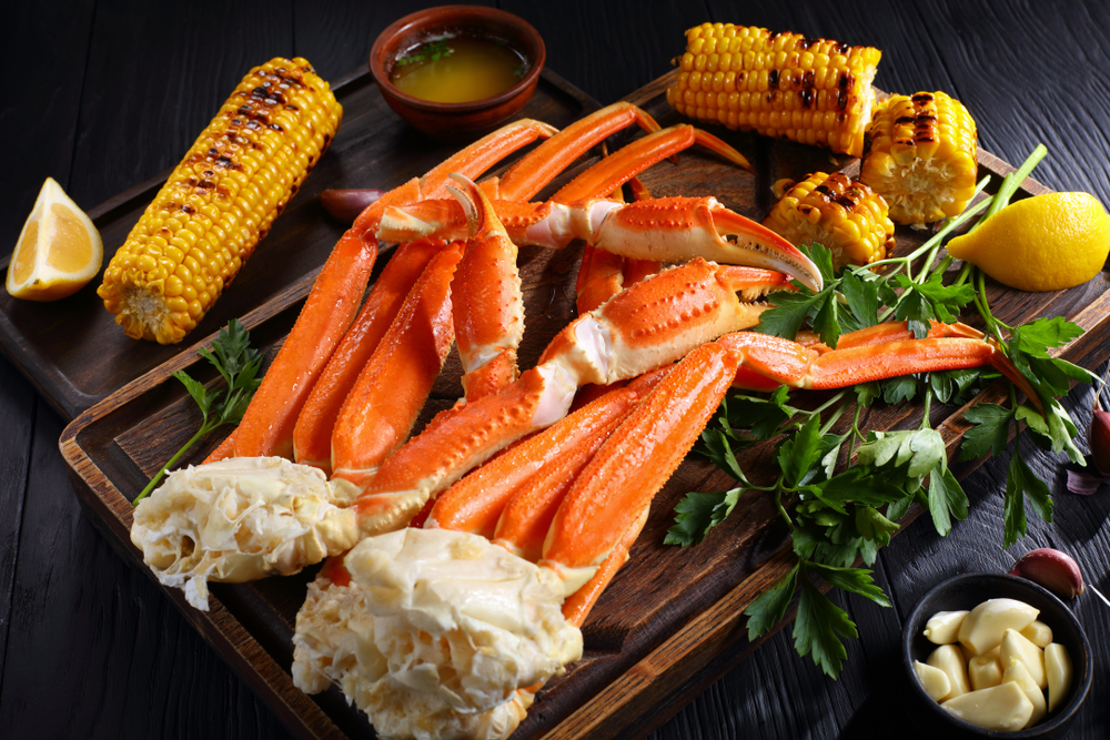 A large platter of snow crab legs with corn, garlic, butter, and lemons