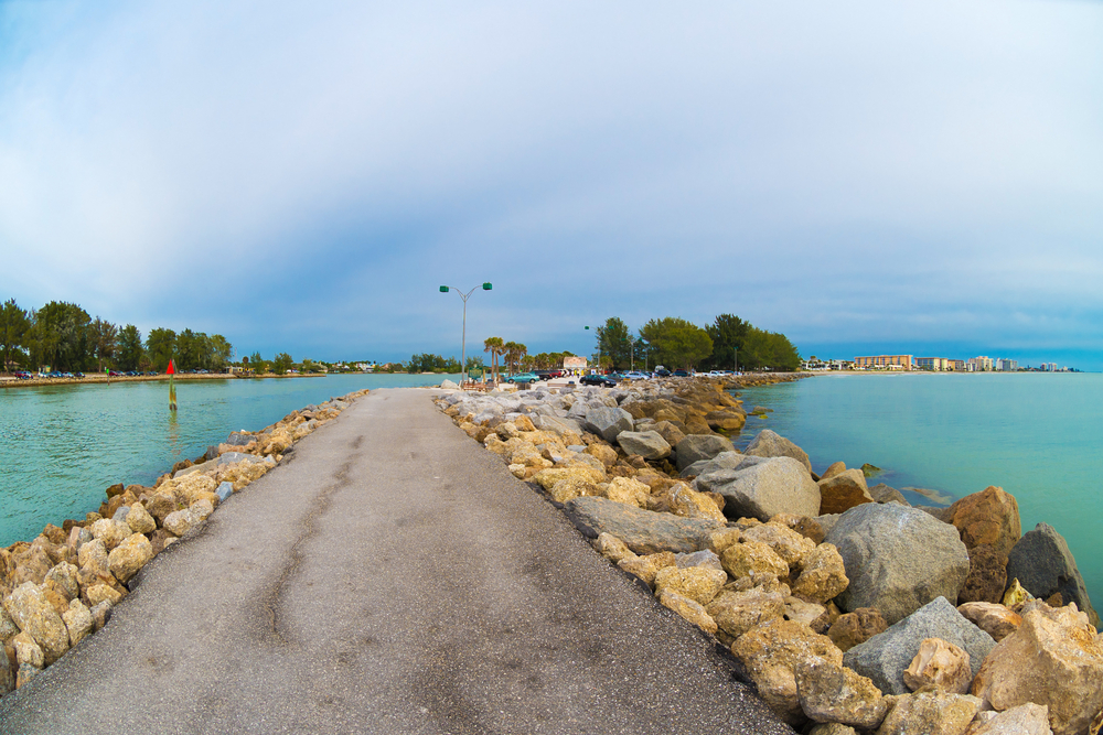 The walkway on the South Jetty with bright blue water on either side along with piles of rocks