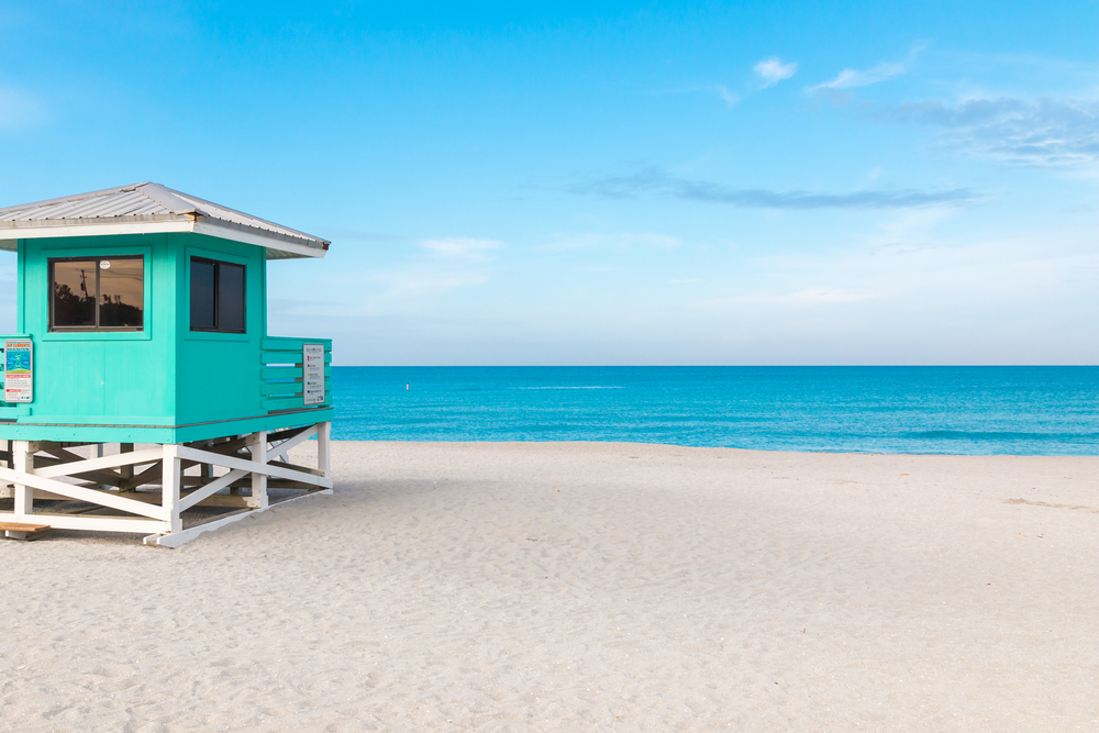 A bright blue lifeguard shack on a white sand beach looking out at bright blue water best things to do in Venice Florida