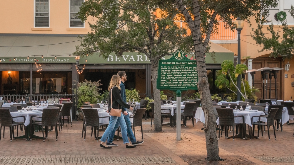 a couple walking by an outdoor restaurant in downtown sarasota. this is one of the places in Florida that looks like Europe with the outdoor tables and cafe style restaurant 