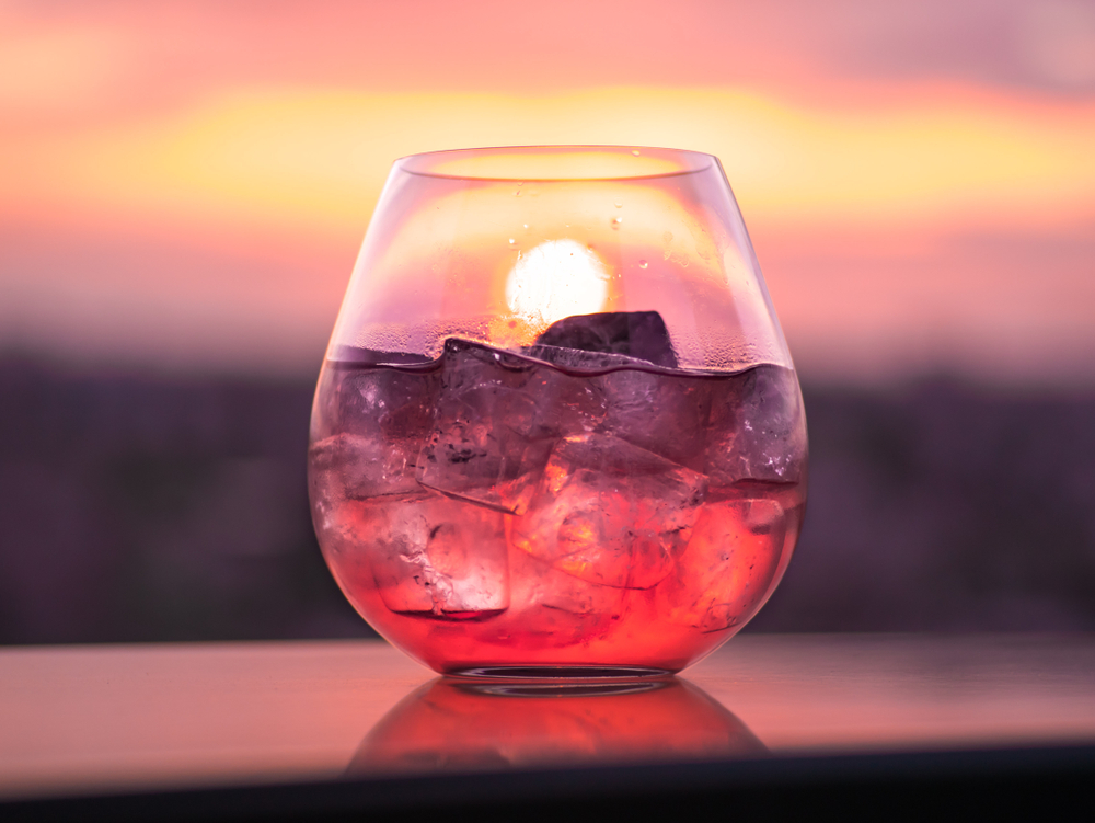 A drink on a ledge with the sunset in the background. 