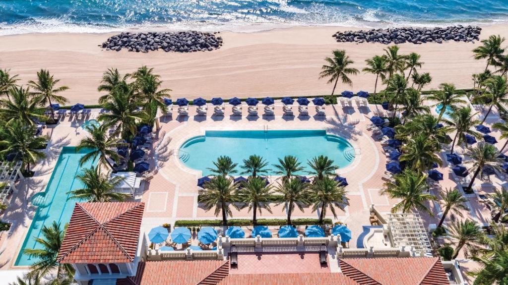 Picture of hotel pool and beach taken from above. There are loungers and umbrellas around the pool. 