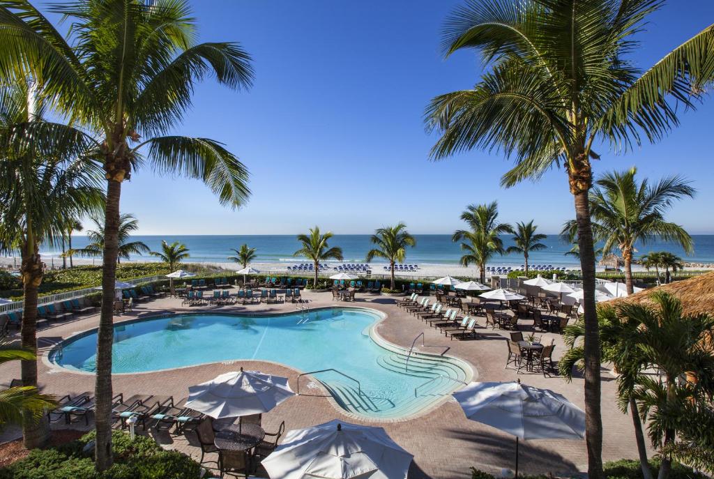 Swimming pool at a resort surrounded by palm trees with the beach in the background. The article is about Florida hotels with a private beach