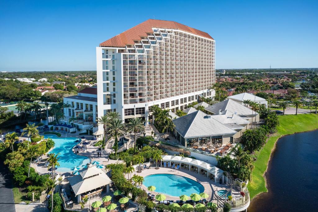 View of high rise hotel surrounded by swimming pools and greenery.  