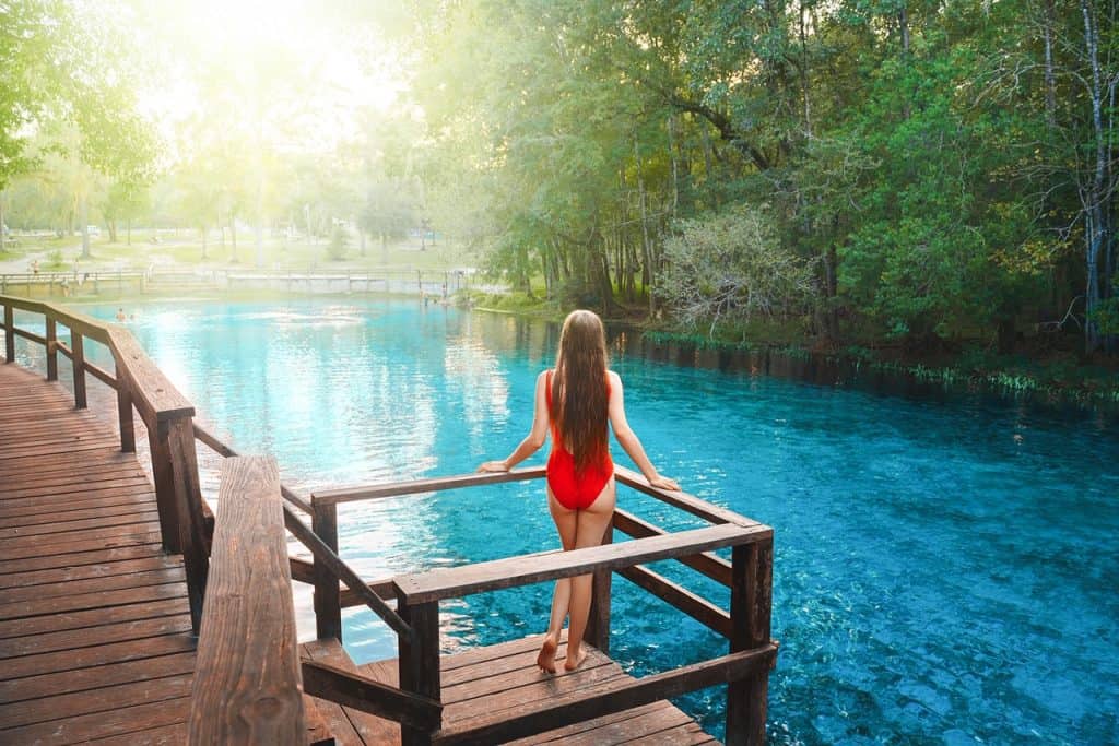 a girl in red swimsuit on a wooden platform overlooking the crystal clear water of the Florida Springs