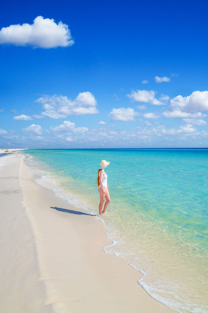 a girl I a white swimsuit in the water along one of the various beaches in our 30 A travel guide