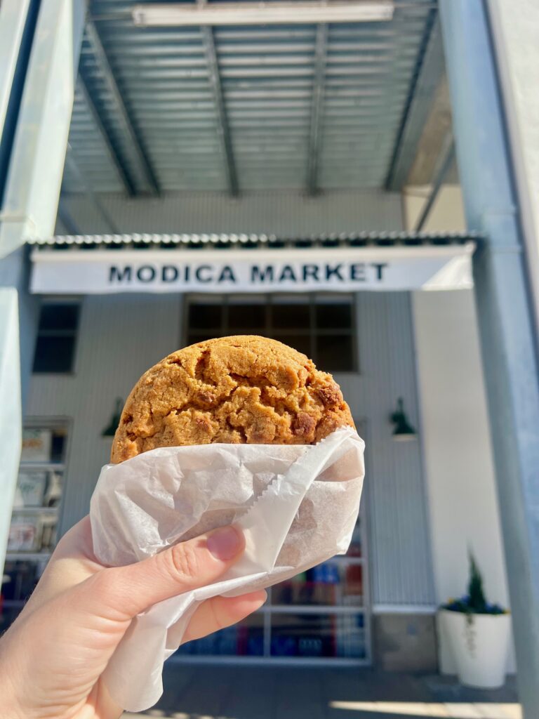 a cookie held in front of Modica Market Seasides to-go market