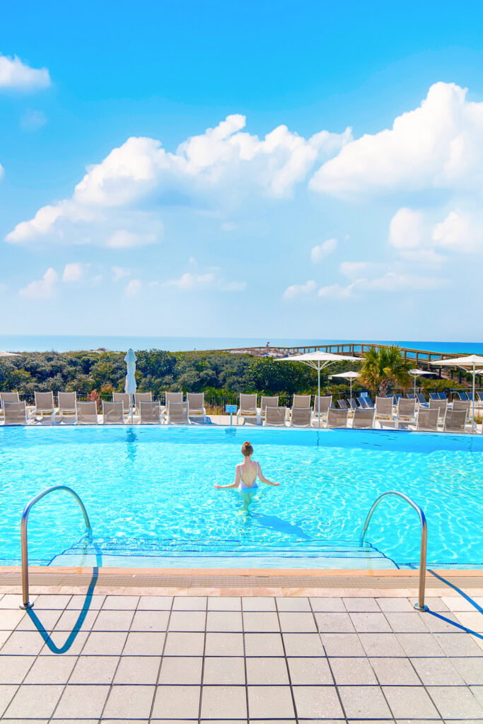 a girl in a white swimsuit in a pool overlooking the ocean