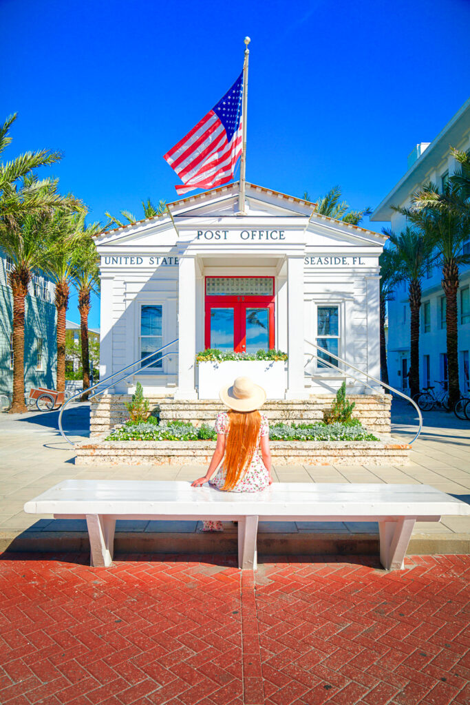 A girl sitting on a bench outside of the Seaside Post Office