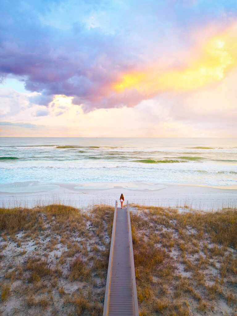 A girl on the boardwalk to the beach at sunset in Watercolor