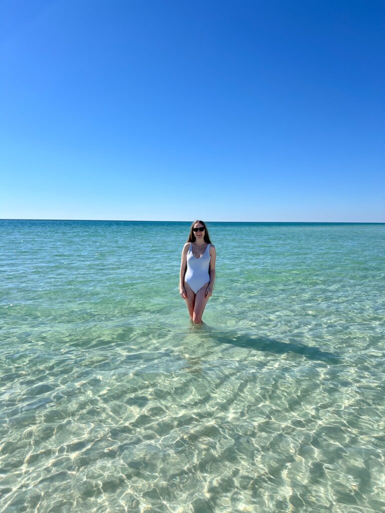 a girl in a white swimsuit standing on one of the beaches along 30A