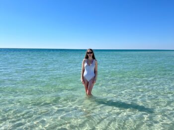 a girl in white swimsuit standing in the ocean on 30A