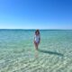 a girl in white swimsuit standing in the ocean on 30A