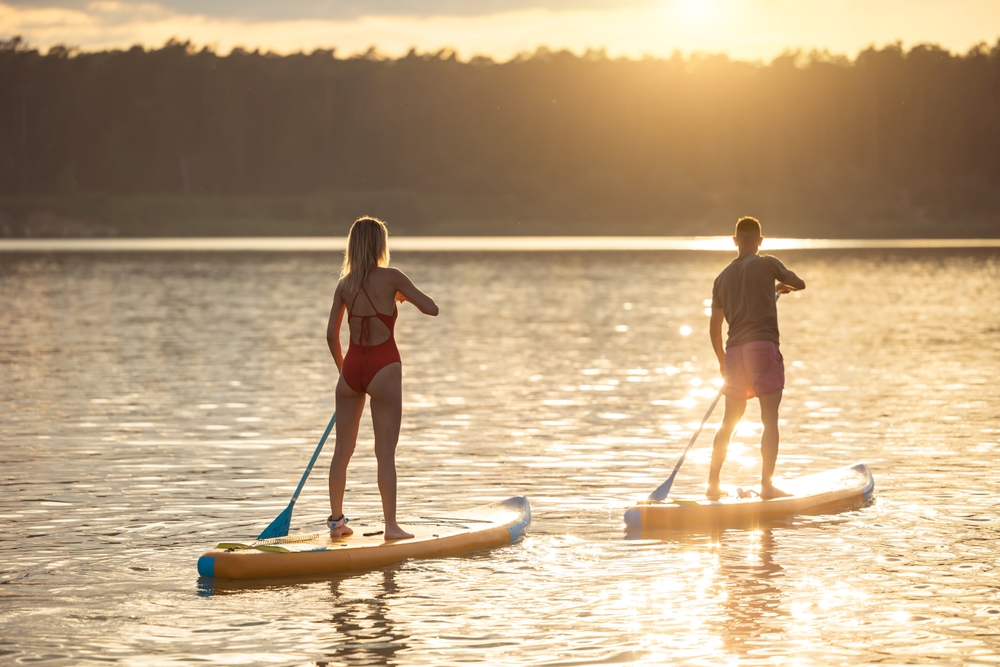 a couple paddle boarding during sunset is one of the best things to do in 30A Florida