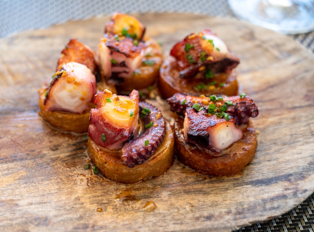 a small plate of appetizer with grilled octopus crostini