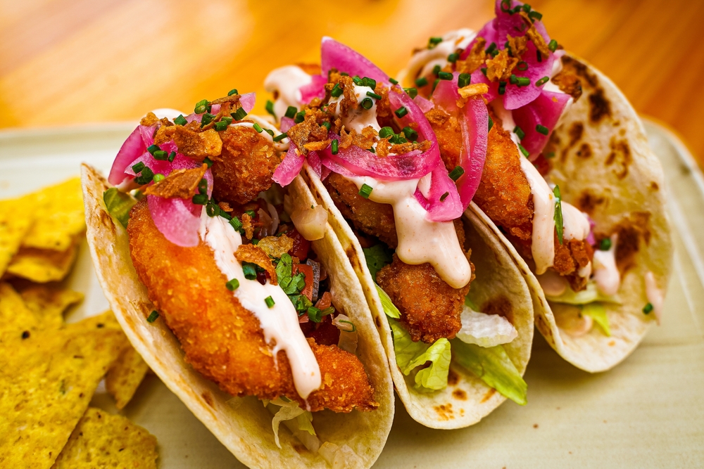 a plate of fried fish tacos with pickled red radish