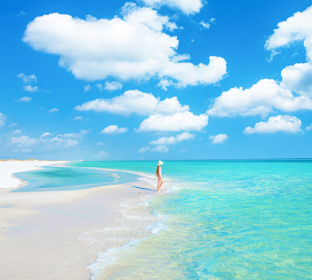 a girl in white swimsuit standing in turquoise waters along 30A beaches a hidden gem in florida