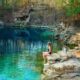 a girl in a bleu swimsuit sitting on the rock edge near one of th many Florida Springs