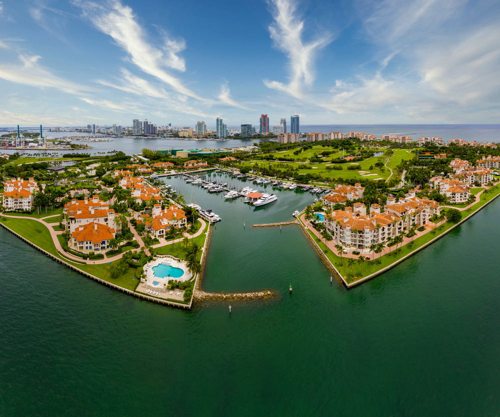 aerial photo of a grassy green island with resorts and skyscrapers 