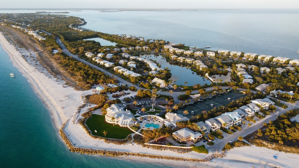 aerial photo of an island that has many houses, swimming pools, and trees. 