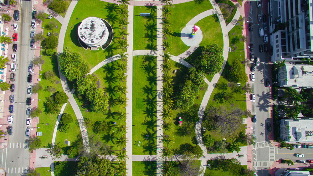 aerial photo of art basel festival week in florida. green space in the middle of the photos and theres a road on each side of it with cars parked along the sides of the roads 