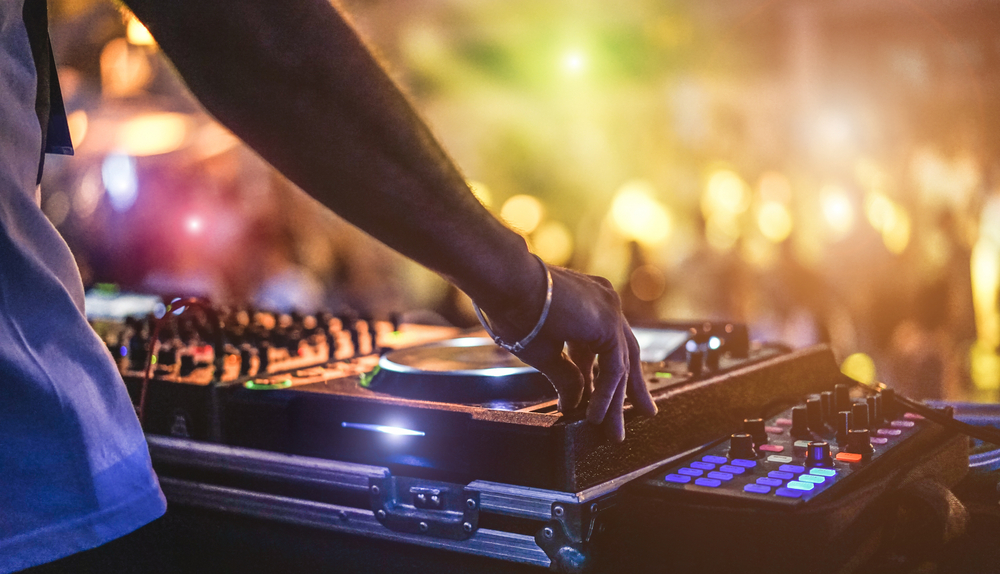 close up of a dj standing next to his turn table at a festival 