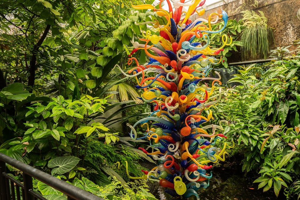 a glass sculpture is standing amongst green vegetation  at the fairchilds gardens spring garden festival 