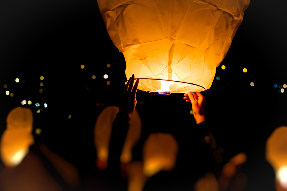 hands are holding a paper lantern in the air as it is about to be released into the night sky at one of the best festivals in florida