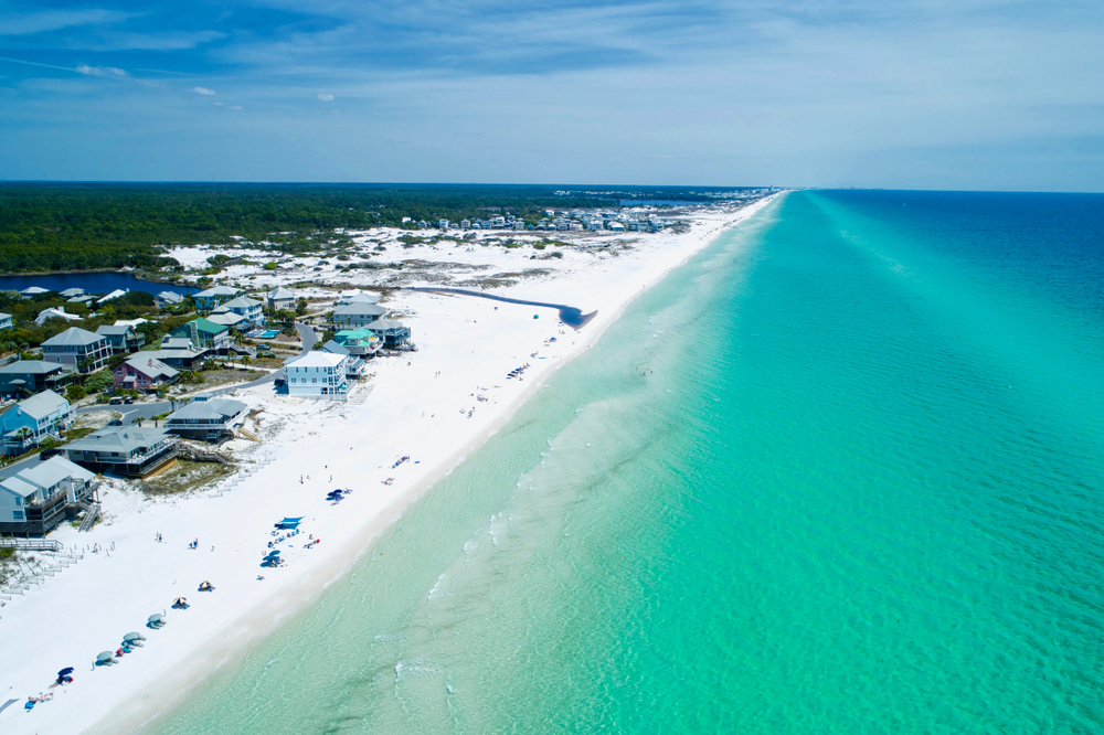 aerial photo of transparent water and white sandy beaches with beach houses on the sand 