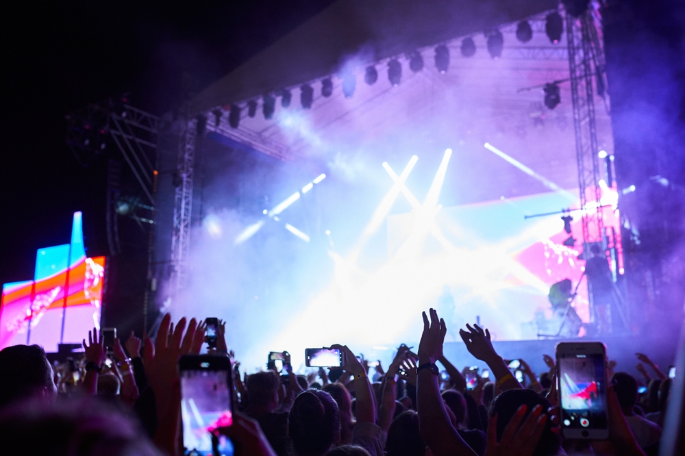 people standing with their arms raised and phones rasied videoing a performance at a music festival