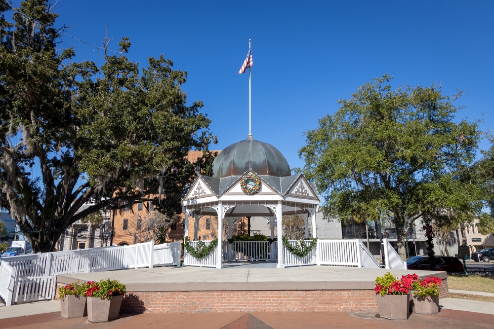 photo of a gazebo, there are trees around the gazebo and a flag coming out of the top of it 