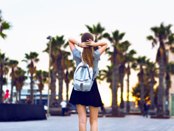 woman in florida in january walking with a backpack and palm trees in the background