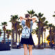 woman in florida in january walking with a backpack and palm trees in the background