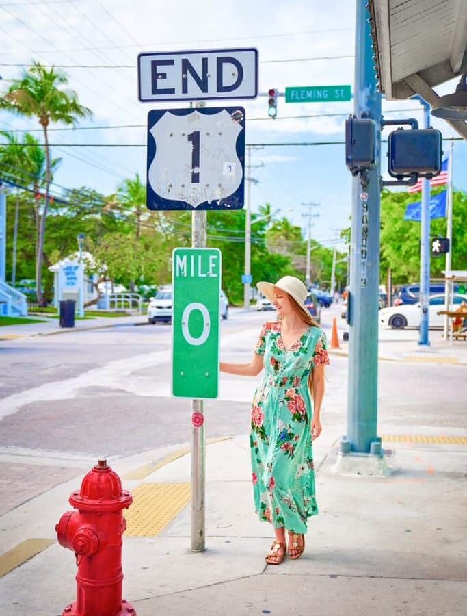 woman standing in green dress at mile 0 in key west