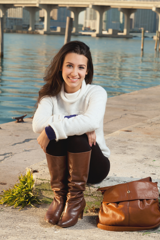 Pretty young woman lifestyle with winter clothing along a seawall on the bay with a downtown skyline at sunset.