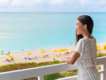 woman standing on the balcony of a florida beach resort and looking out over the ocean