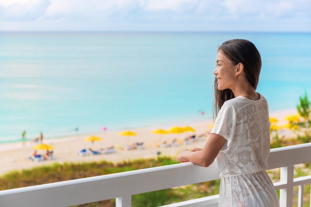 woman standing on the balcony of a florida beach resort and looking out over the ocean