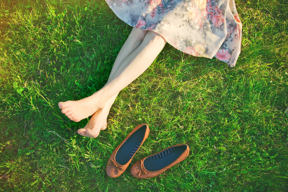 girls legs lying in grass barefoot without shoes